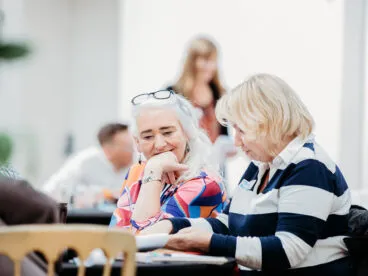 People sat at a table having a conversation over some notes