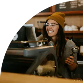 Lady wearing beanie hat making coffee in a cafe