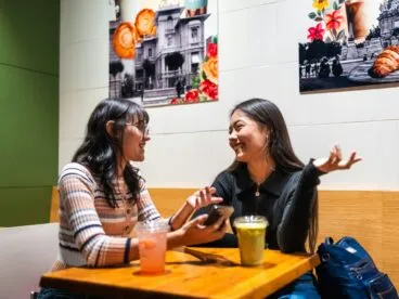 Two young woman talking at a cafe table