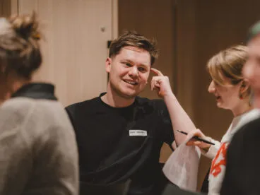A person smiles while in conversation with a group around them